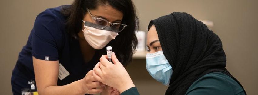 Amna Kahn, a first-year student at the University of Maryland School of Pharmacy (right), learns how to prepare COVID-19 vaccine doses.