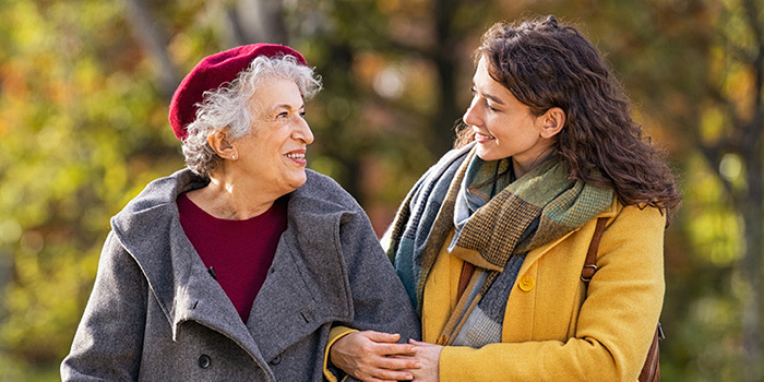 A younger woman walks arm in arm with an older woman