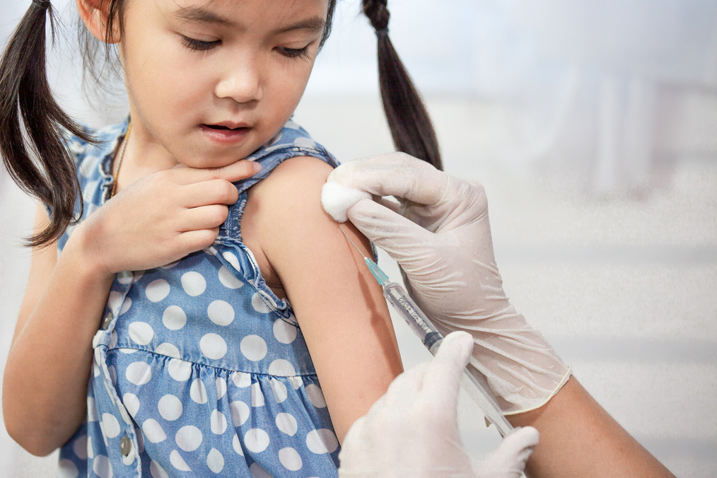 Doctor injecting vaccination in arm of Asian girl, healthy and medical concept.