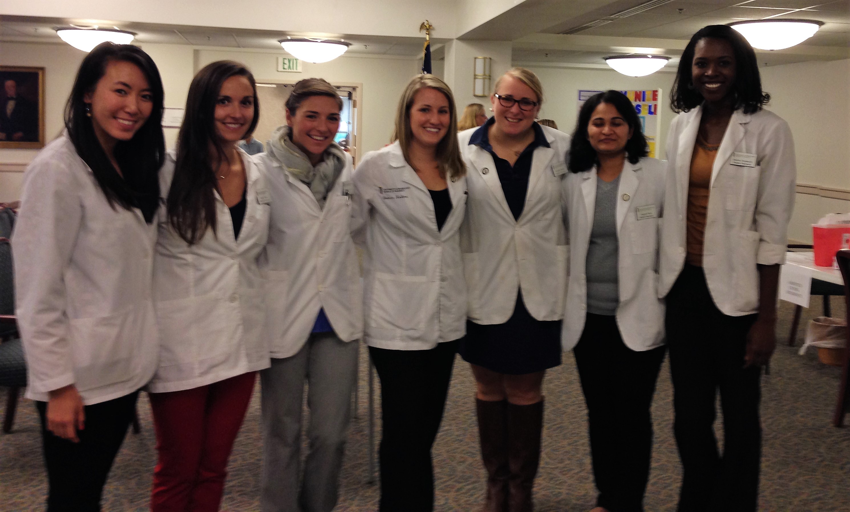 Group of students smiling for a photo in white coats