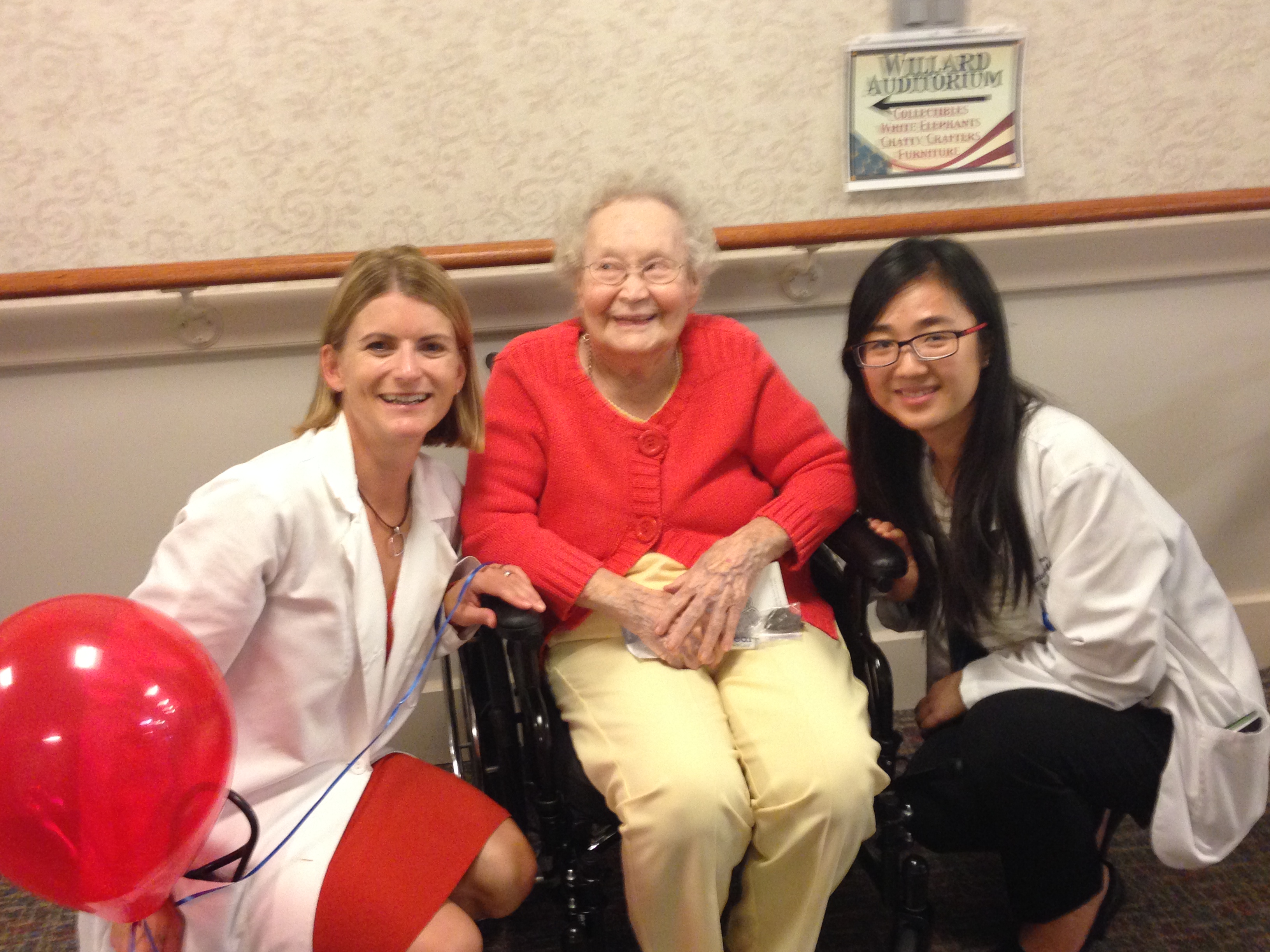 Two medical professionals and elderly woman in wheelchair smiling