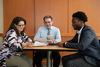 Three People at a table that seem to be working on something.