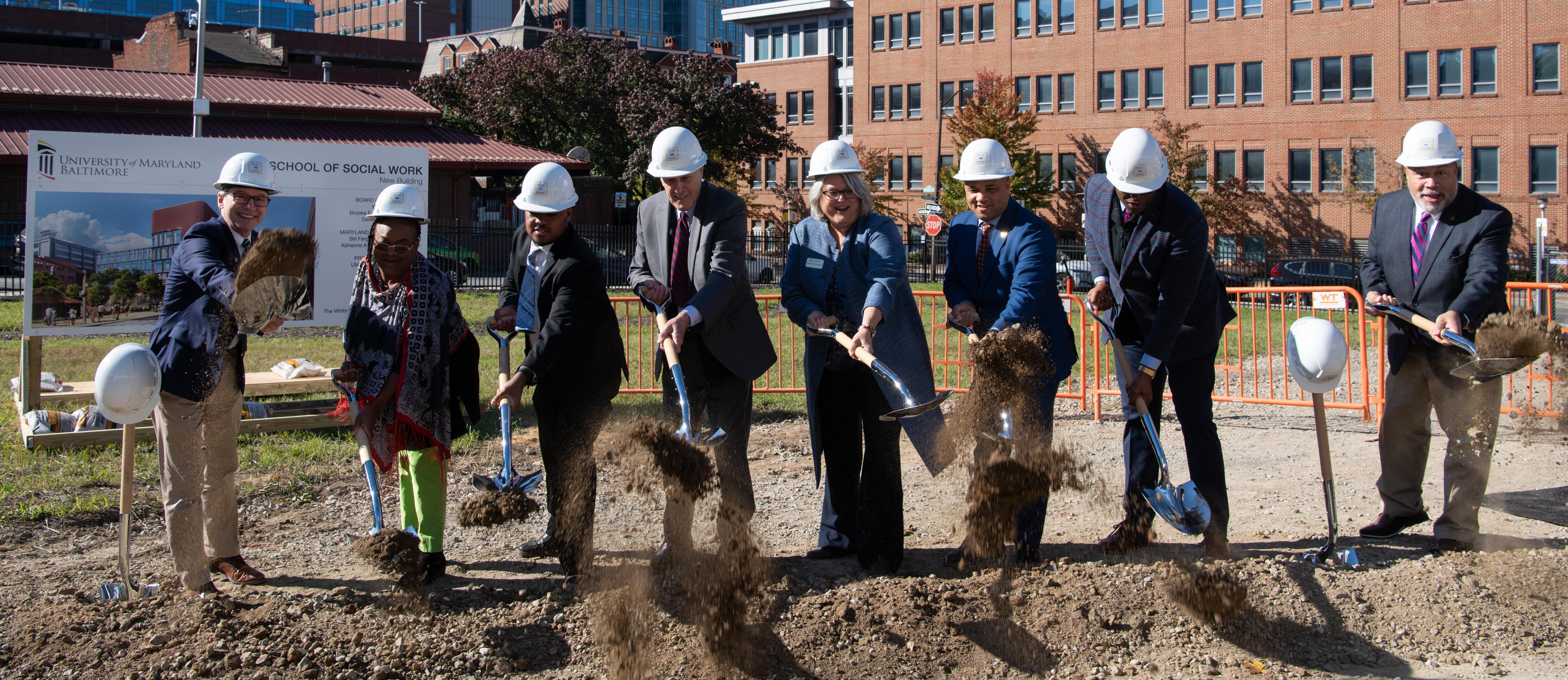 group of people with shovels breaking ground