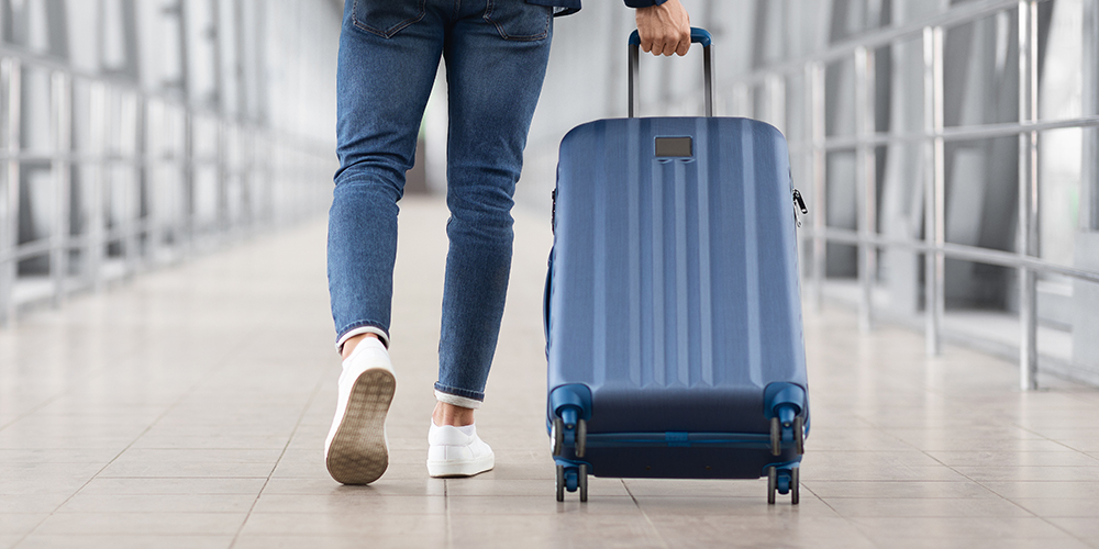 A traveller pulls their wheeled luggage