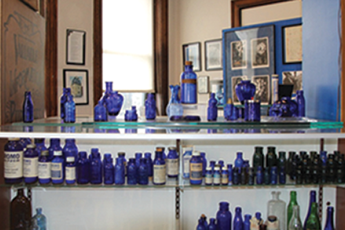 Blue glass bottles lined up in a display case