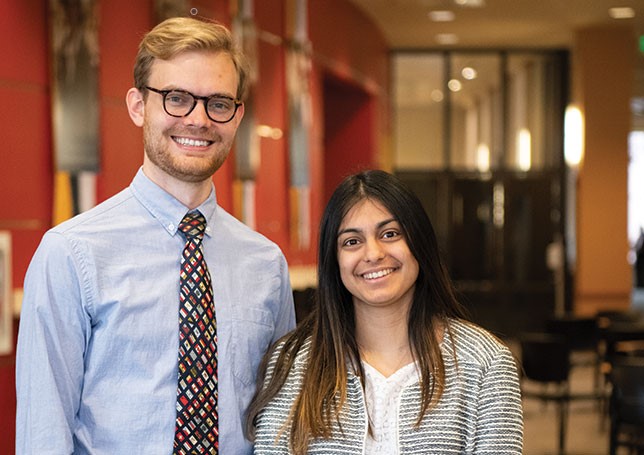 Male and female student pose in hallway