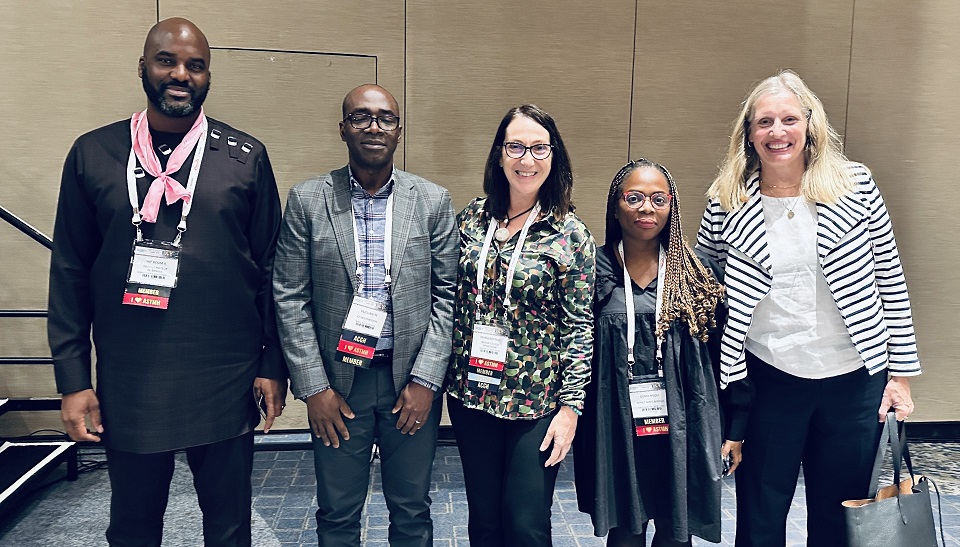 Five people attending a conference pose for a photo