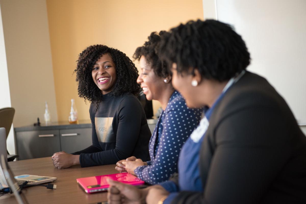 Three black women sit at a table for panelists