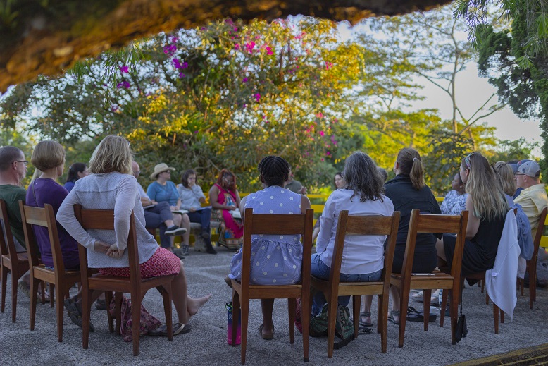 A group of people sit in a circle outside