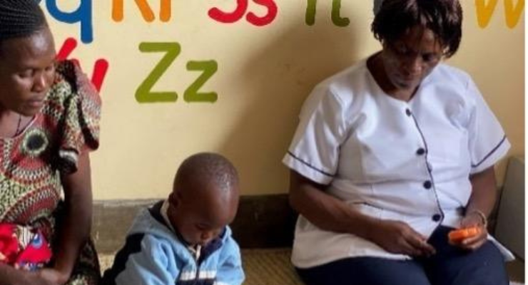 Two women watch a child play