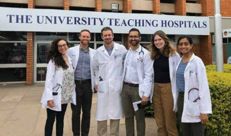 Faculty and students in medical jackets stand outside a hospital in Zambia