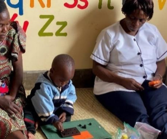 Two women watch a child play