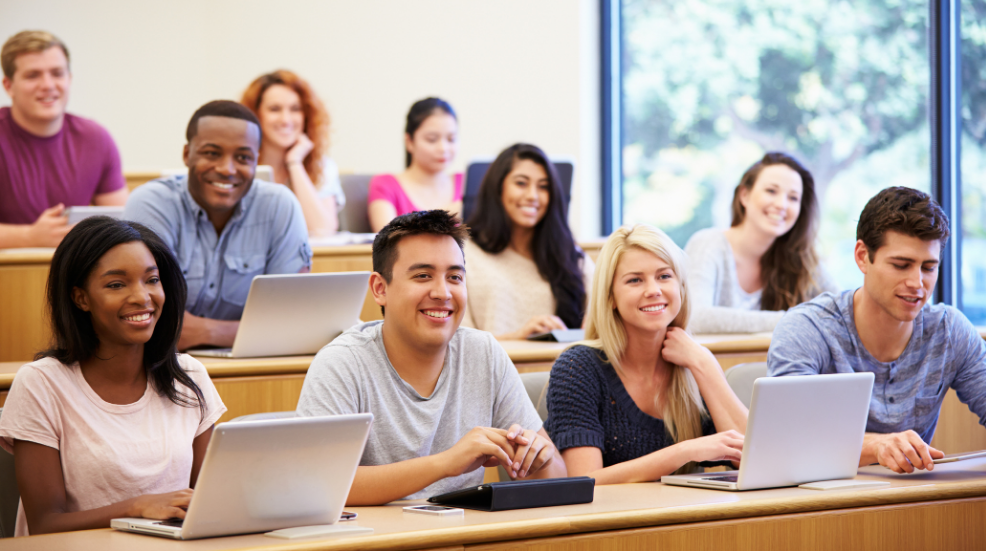 College students sit at desks in a classroom.