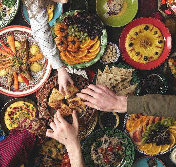 A variety of Indian dishes with hands reaching for dishes.