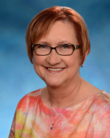 Headshot of a woman wearing glasses with a blue background