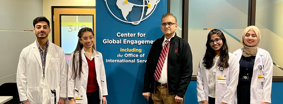 Four students and a doctor from Pakistan pose for a photo outside the Center for Global Engagement suite.