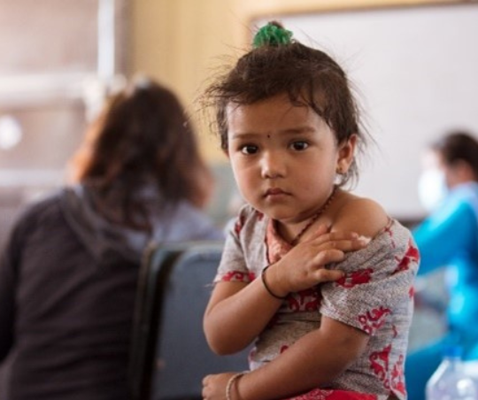 A young girl holds her arm where she received a vaccination