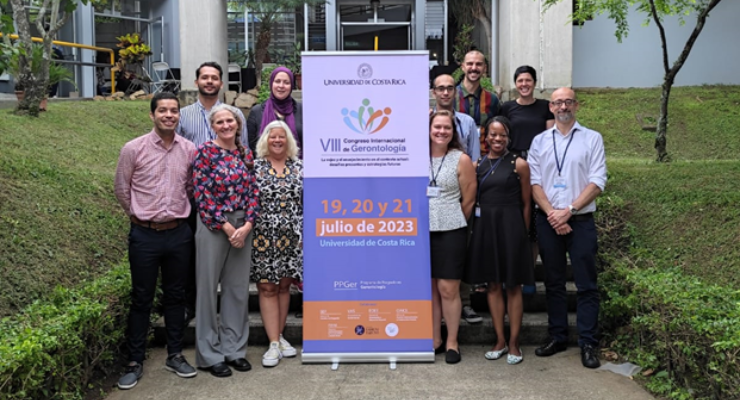 Faculty pose for a group photo beside a banner in Costa Rica