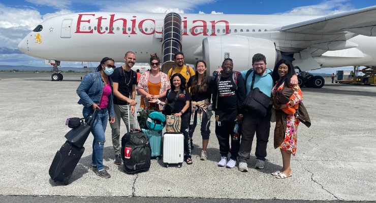 Students and faculty pose for a photo in front of an airplane