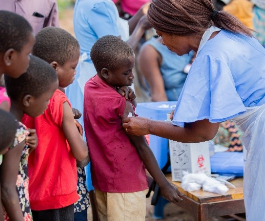 A woman gives a shot to a child while others wait in line