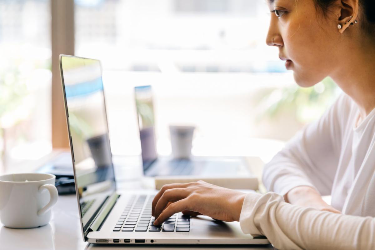 Woman Typing on Laptop in Cafe