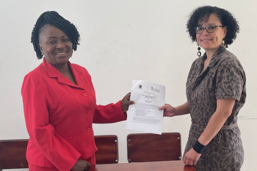 Two women hold a document between them