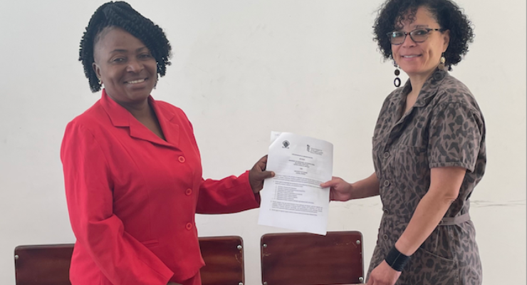 Two women hold a document between them