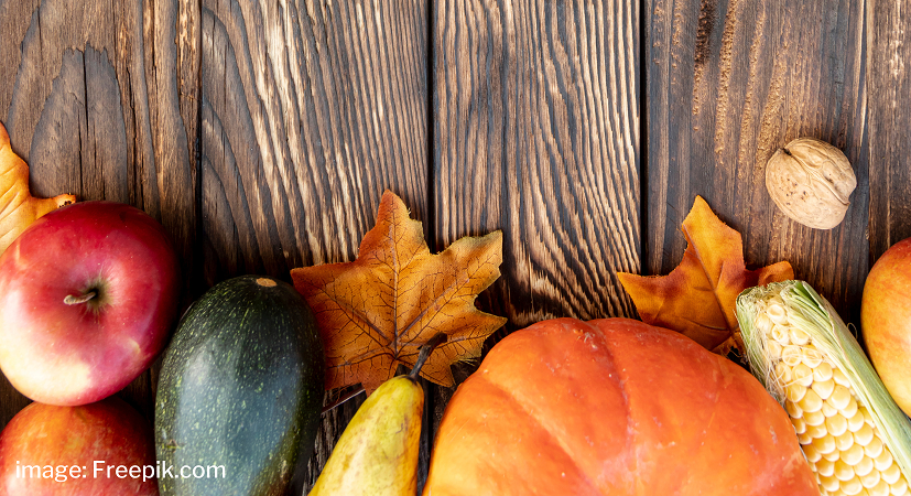 A selection of fall vegetables and leaves on a wood surface