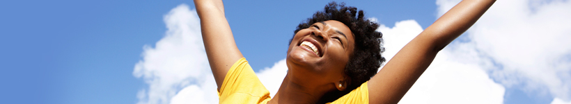 woman in yellow shirt celebrating in front of blue sky