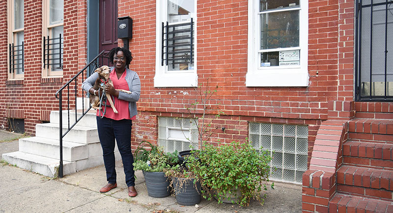 Khandra Sears holding her dog in front of her home