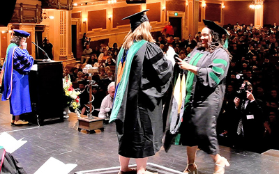 Medical student celebrates receiving doctoral hood.