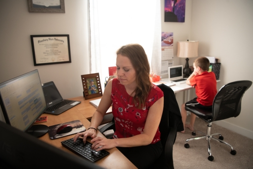 Carolyn Apanavage, BSN, RN-BC, CEN, of Managed Care Advisors works as a medical case manager for the UMB COVID-19 Hotline from her New Market home as her son, Brayden, attends virtual school in the background.