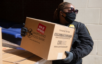 UMB police officer carrying Maryland Food Bank box.