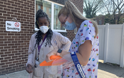 Hayley Carper, RN, a student at the University of Maryland School of Medicine (right), helps Seretha Ellerbe, a West Baltimore community members (left), get registered for a vaccination appointment. 