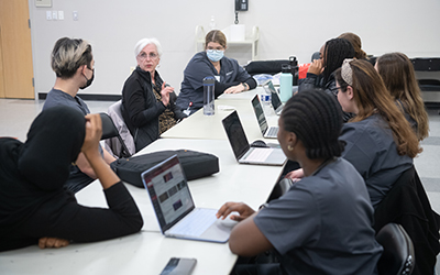 Patricia Zimberg, JD, MS, RN, an adjunct faculty member teaching one of the cohorts of the Clinical Care Across the Continuum class at the Waverly Branch, talks with nursing students.