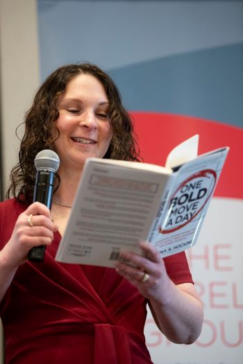 Shanna Hocking, founder and CEO of Hocking Leadership, LLC, reads an excerpt from her book, “One Bold Move a Day: Meaningful Actions Women Can Take to Fulfill Their Leadership and Career Potential,” during the 2024 UMBrella Women’s History Month Symposium.