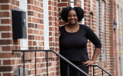 Rajaniece Thompson, a new homeowner through UMB's Live Near Your Work Program, stands in front of her new home in Pigtown.