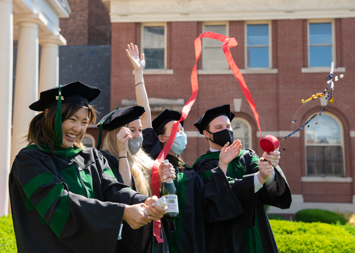 Graduates from the University of Maryland, School of Medicine celebrate after graduating and recieving their hoods in front of Davidge Hall.