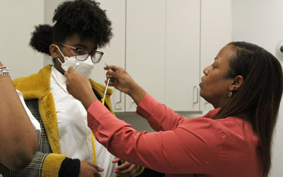 Kimberlee Bizzell, MD, the medical director and assistant professor, UMB Physician Assistant Program, assists the students with their stethoscopes.