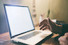 a hand hovering above a laptop keyboard