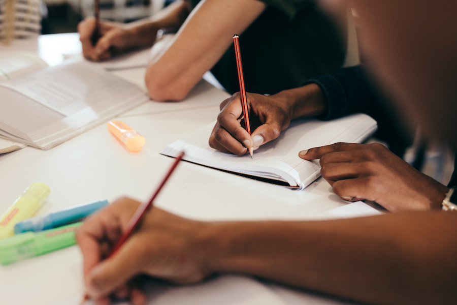 three students writing at a table