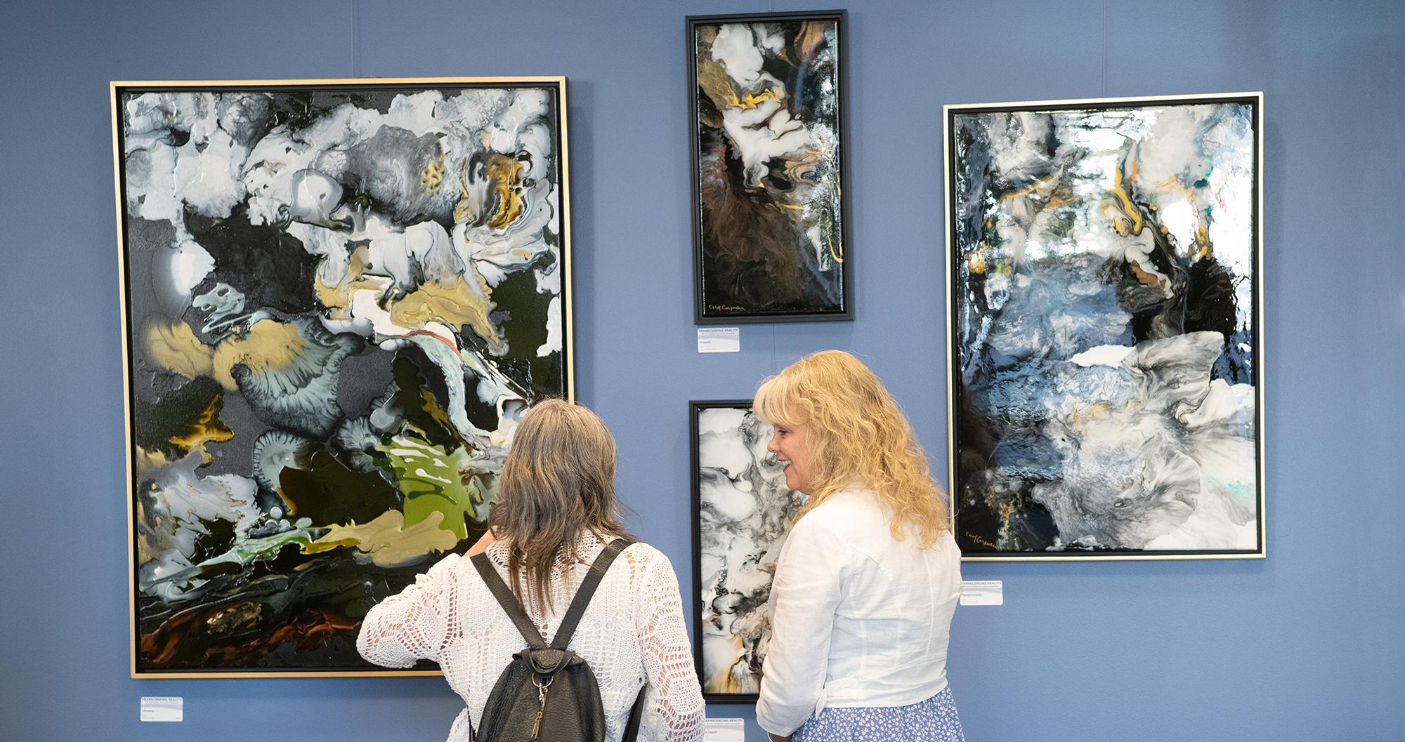 Two women looking at paintings