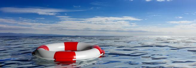 Red and white life ring floating in the water under dark blue sky